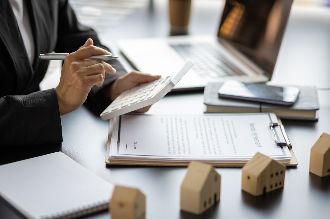 Ideen zur Hausvermietung, Kredite, Hypotheken und Immobilienbewertungen zum Verkauf. Eine Geschäftsfrau in einem Bankbüro berechnet eine Hypothek.